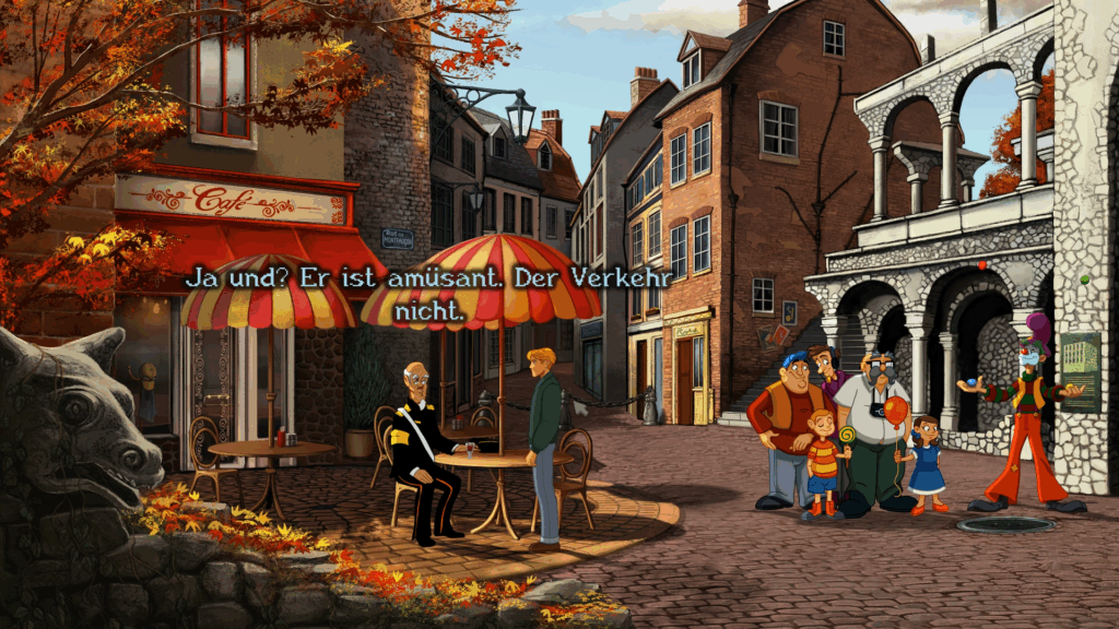 Screenshot aus Baphomets Fluch Reforged: eine sonnige Kopfsteinpflaster-Gasse mit Backsteingebäuden und herbstlich-orangenen Bäumen. Links ein Café mit rot-gelb gestreiften Markisen und einem Tisch, an dem ein uniformierter Mann sitzt; gegenüber steht George in grüner Jacke. Rechts versammelt sich eine kleine Gruppe aus Erwachsenen und zwei Kindern bei einem bunt gekleideten Straßenkünstler, der die Arme ausbreitet. Im Vordergrund eine steinerne Wasserspeier-Skulptur; eingeblendeter deutscher Dialog: "Ja und? Er ist amüsant. Der Verkehr nicht."