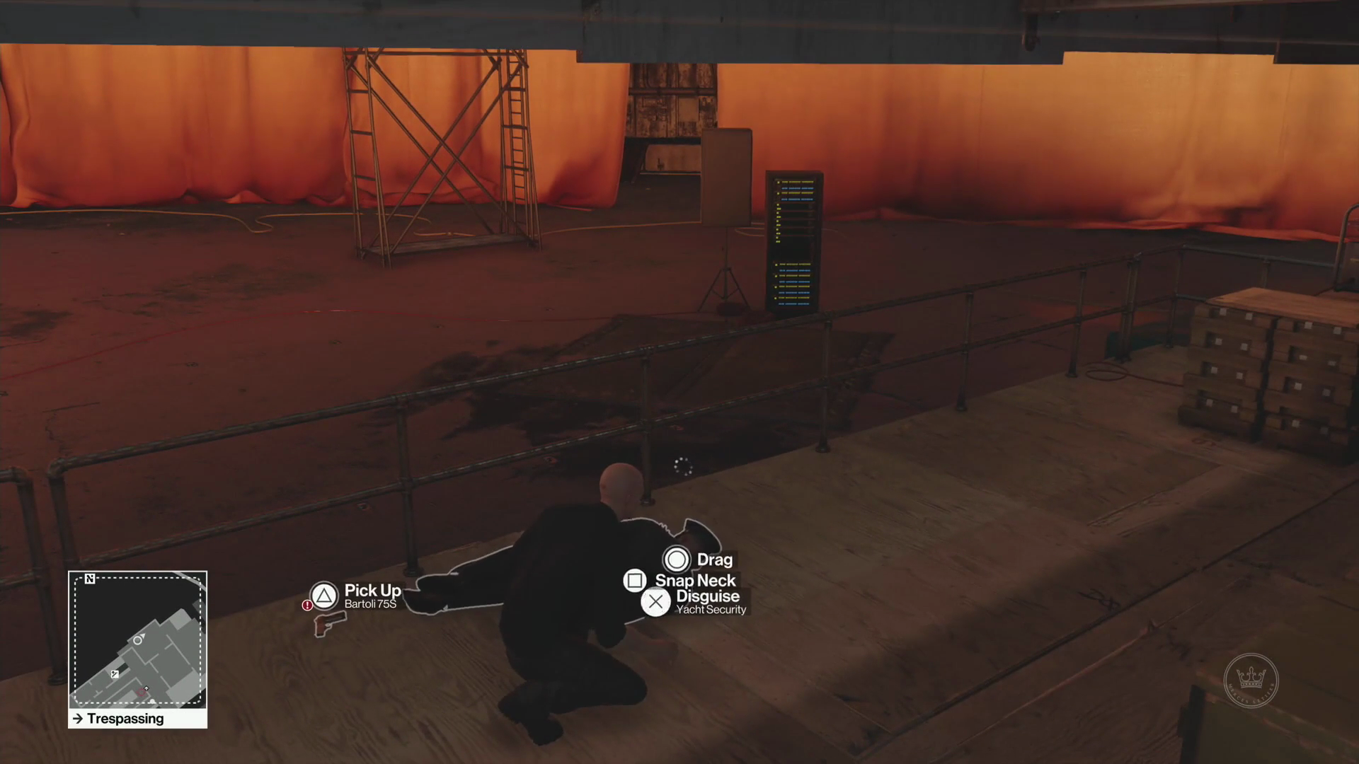 Screenshot aus HITMAN: Agent 47 kniet auf einem Deck der Yacht-Kulisse, im Hintergrund ist ein Malergerüst und ein Serverschrank zu sehen, orange Stoffbahnen deuten einen Sonnenuntergang an. In einer Lücke ist dahinter eine grobe Betonwand sichtbar.
