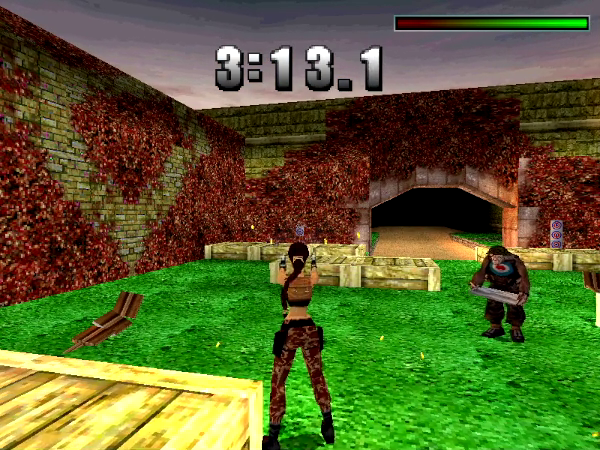 Ein Screenshot aus Tomb Raider III, der Lara Croft bildmittig auf einem Outdoor-Schießstand zeigt. Rechts von ihr ein Butler mit einem Silbertablett und einer Schutzweste, auf der eine Zielscheibe aufgemalt ist. Im Hintergrund eine Backsteinmauer mit einem Tordurchgang, die den Schießstand begrenzt.